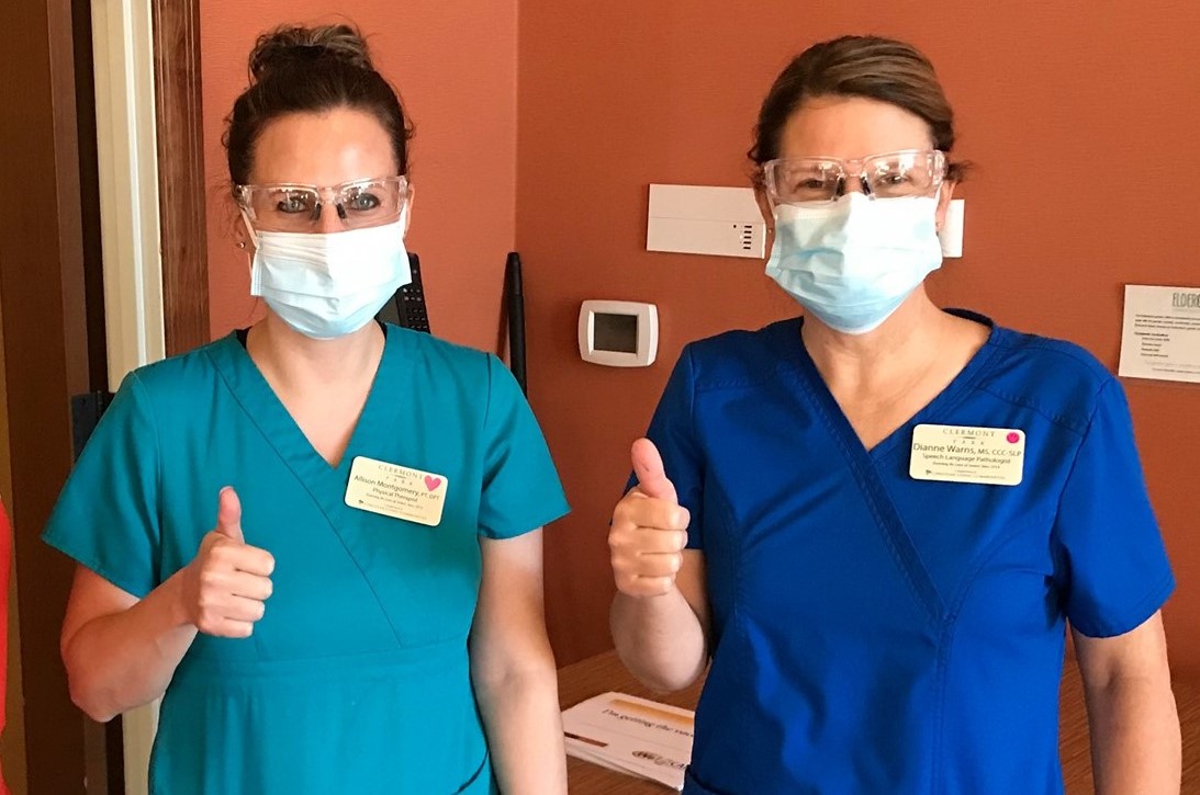 Nurses pose with thumbs up in masks.