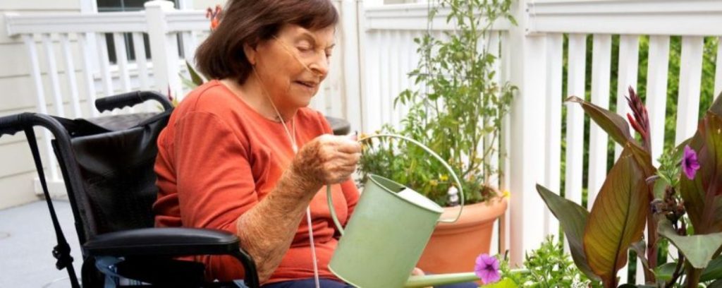 Holly Creek resident watering flowers on her patio