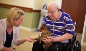 Care partner talking with resident and his pet chihuahua