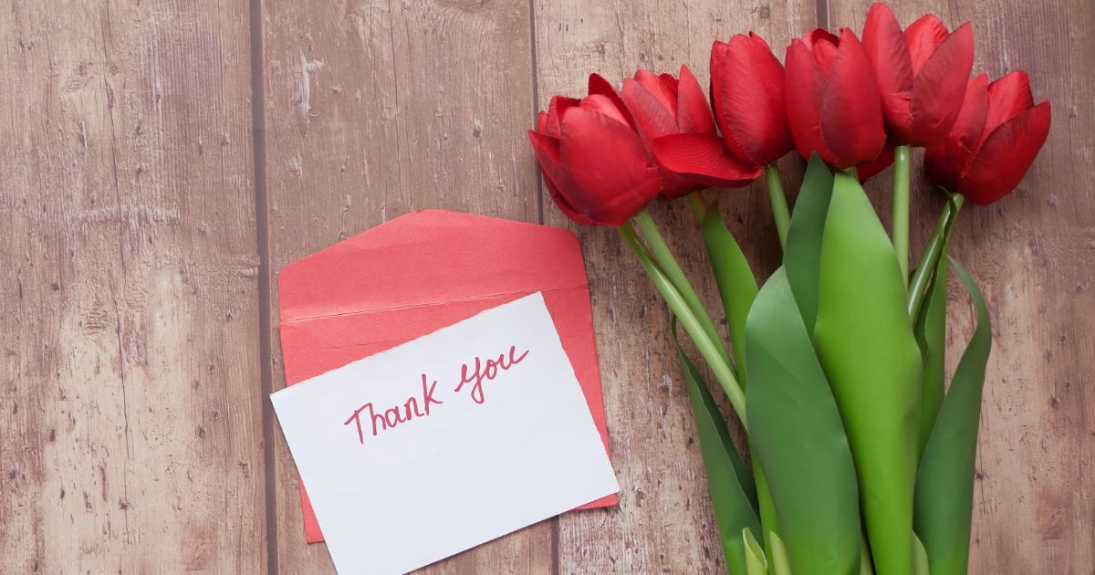 Thank you card next to bouquet of flowers